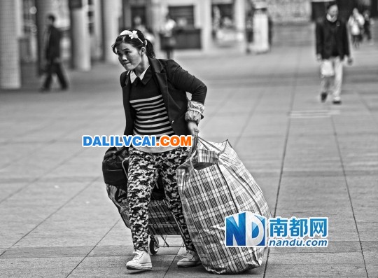 在佛山火車站正準備返鄉(xiāng)的鋁材廠工人拖著旅行包